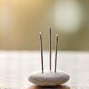 Fine acupuncture needles on a balanced stone background